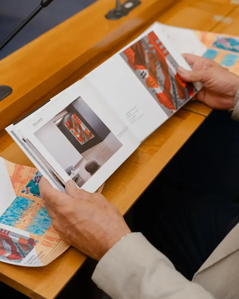 il catalogo delle opere di Paolo Mariani viene sfogliato da un partecipante alla prsentazione